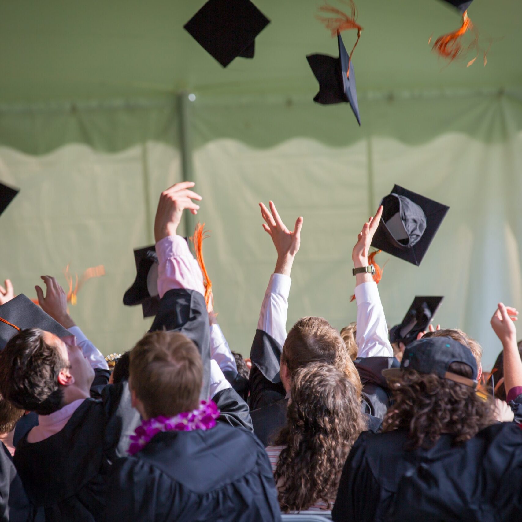 A group of graduates tossing their hats into the air a their graduation ceremony.