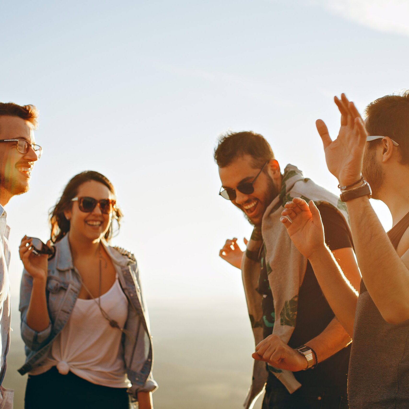 Four happy group of young adults having fun and dancing in a circle.